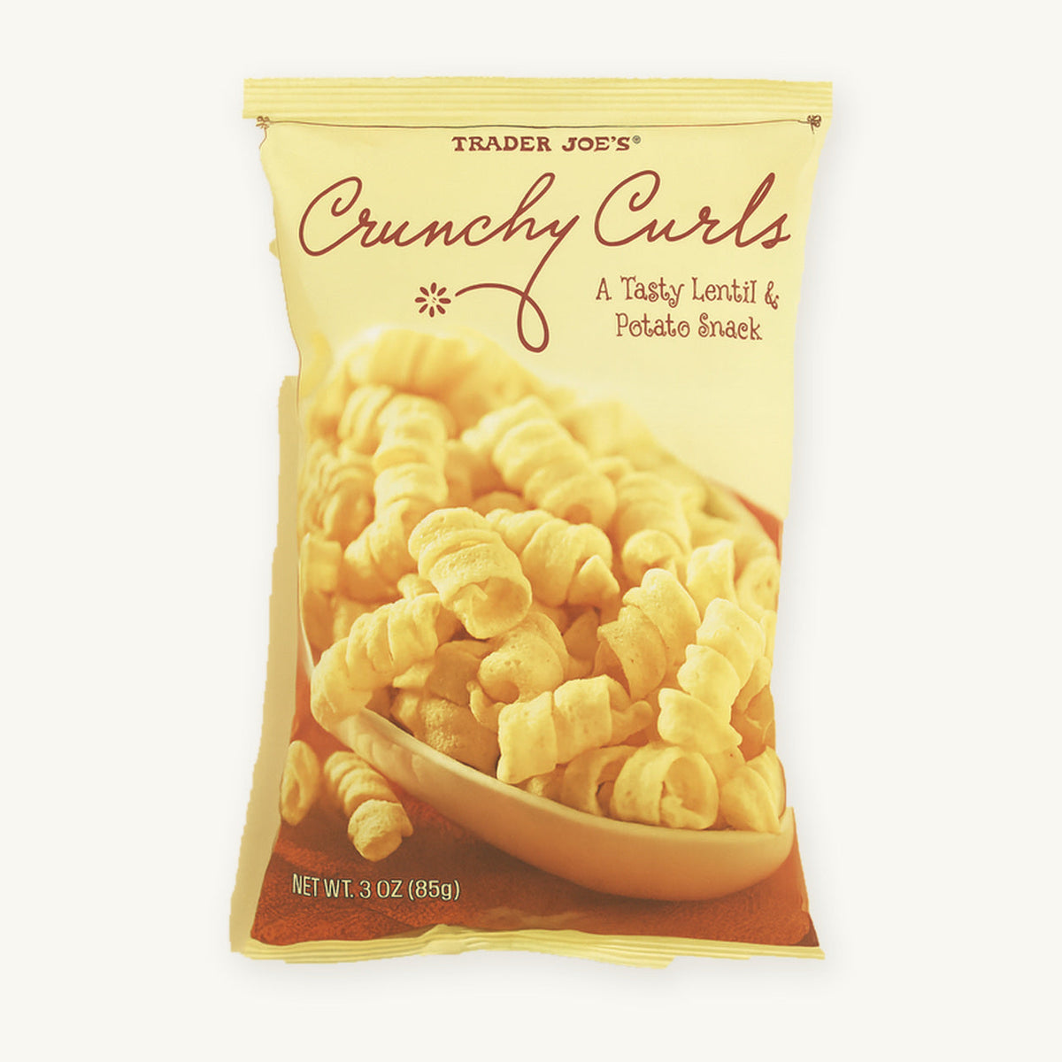 Trader Joe's Crunchy Curls. Yellow bag showing curled snacks on a warm ivory background.